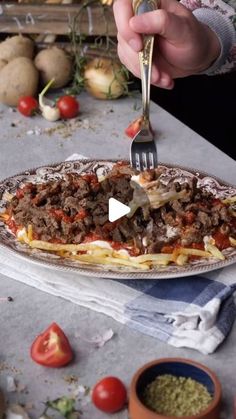 a person is cutting into a pizza on a table with tomatoes and other food items