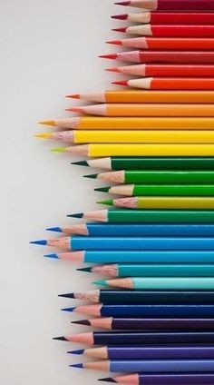 many colored pencils lined up in the shape of a rainbow