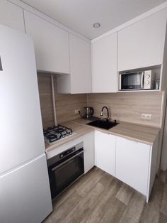 a kitchen with white cabinets and wood flooring next to a refrigerator freezer oven