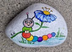 a painted rock with a caterpillar and flower on it