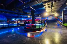 an empty parking garage with blue lights and red neons on the side walk area