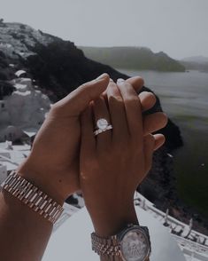 two people holding each other's hands with the ocean in the background