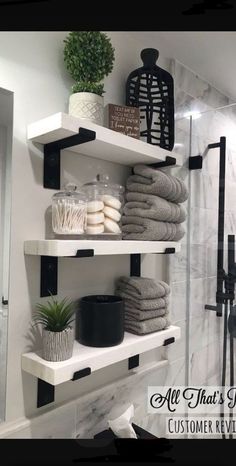 bathroom shelves with towels, candles and plants on them in black and white decorating