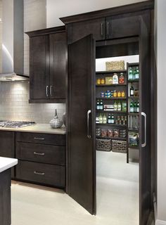 an open pantry in the middle of a kitchen with dark wood cabinets and white counter tops