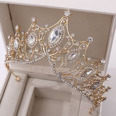 a gold tiara with crystal stones in it's crown box is displayed for the camera
