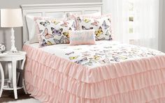 a bed with pink ruffled bedspread and two pillows on top of it