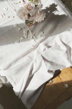 a vase filled with flowers sitting on top of a table covered in white linens