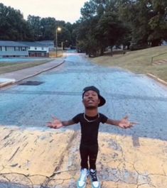 a young boy standing on the side of a road with his arms outstretched in front of him