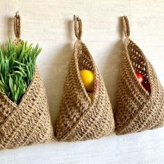 three baskets are holding fruit and vegetables on the wall, one is made out of jute