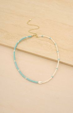 a blue and white beaded necklace on a wooden surface