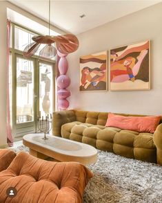 a living room filled with furniture and paintings on the wall above it's windows