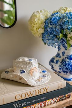 a blue and white vase sitting on top of a book next to a flower pot