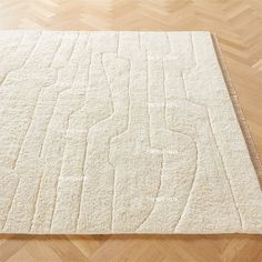 a large white rug on top of a wooden floor next to a wood flooring board