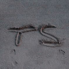 the word love is written in the sand with two footprints next to it and an animal's tail sticking out