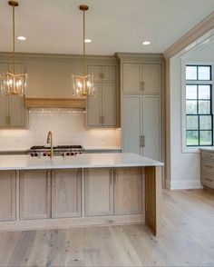 a large kitchen with an island in the middle and two lights hanging from the ceiling