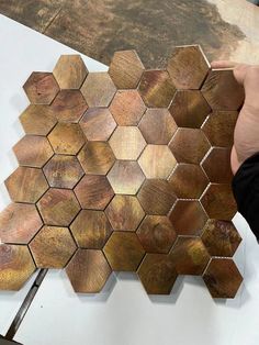 a person is working on some wood pieces with a metal tool in their hand and hexagons are placed around the edges