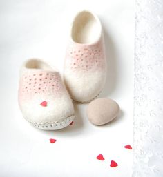 a pair of baby shoes sitting on top of a white table next to a heart shaped object