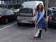 a woman in a plaid skirt is on a scooter and smiling at the camera