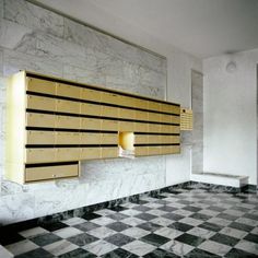 an empty room with checkered flooring and gold lockers on the wall above it