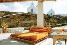 an outdoor patio with chaise lounges and tables on the deck, overlooking a rocky hillside