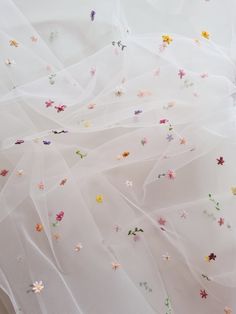 white fabric with colorful flowers on it and sheer tulle over the top, as seen from above