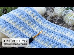 a crocheted blue and white bag with an umbrella on it next to flowers