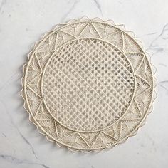 two white plates sitting on top of a marble counter next to each other, one with an intricate design in the middle