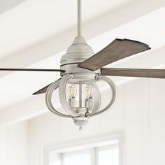 a ceiling fan with two light bulbs hanging from it's blades in a white room