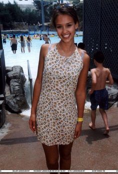 a young woman standing in front of a swimming pool with her hands on her hips