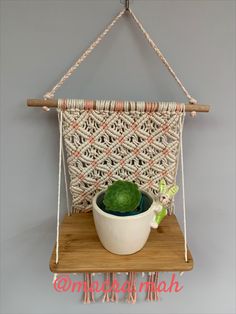 a white bowl sitting on top of a wooden shelf next to a green potted plant