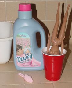 a bottle of downy liquid next to a cup with toothbrushes in it