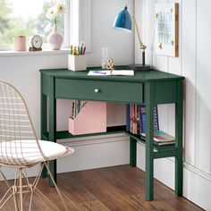 a green desk with some books on it and a chair in front of the window
