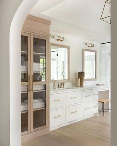 a large bathroom with white cabinets and wood flooring, an arched doorway leading into the room