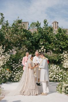 a man and woman standing next to each other in front of flowers on the ground