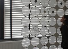 a woman standing in front of a wall made out of circles and circles hanging from the ceiling