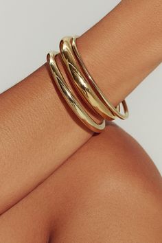 a woman's arm with three gold rings on it