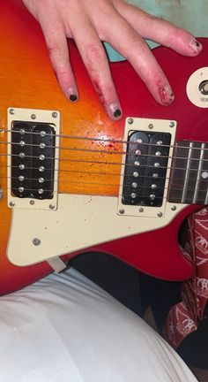 a woman's hand on top of an electric guitar