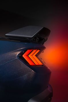 the back end of a blue car with an orange tail light