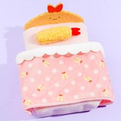 a pink and white blanket with a stuffed animal on it's top, sitting on a purple surface