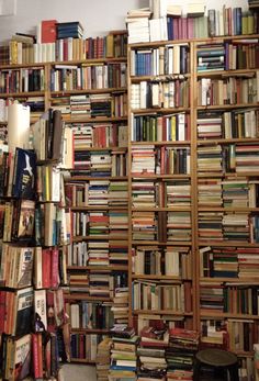 a room filled with lots of books next to a wall covered in bookshelves