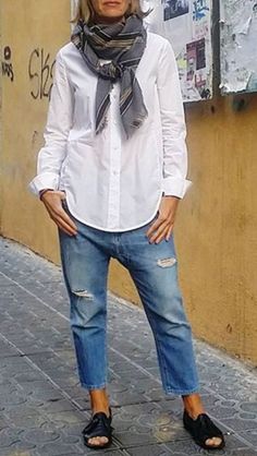 a woman in white shirt and jeans standing on sidewalk