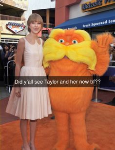 a woman in a white dress standing next to an orange and yellow stuffed animal with the caption did you see taylor and her new off?