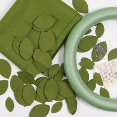 paper leaves and other crafting materials are arranged on a white tablecloth with green circles