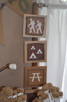 several wooden signs with symbols on them in front of a window and some white curtains