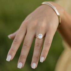 a woman's hand wearing a ring with a diamond in the middle and a gold band around her wrist