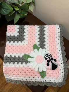 a crocheted blanket with a ladybug and flower design on the bottom