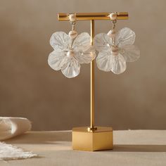 a pair of flower shaped glass earrings on a gold stand