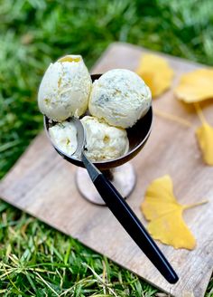 three scoops of ice cream sitting on top of a wooden board next to leaves