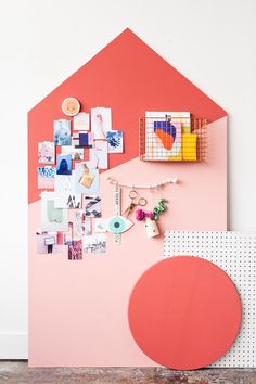 a pink wall with pictures and magnets on it, next to a red table