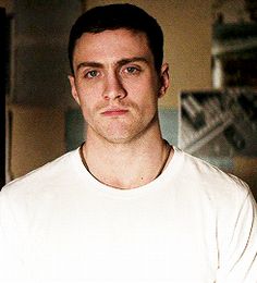 a man in a white t - shirt is posing for the camera